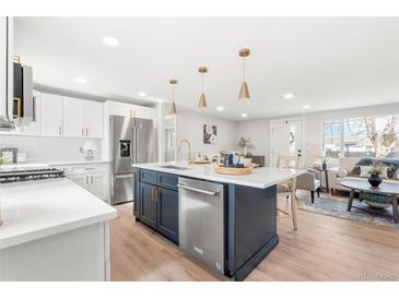 Modern kitchen with white cabinets, a large island, and stainless steel appliances at 1070 W Oxford Ave, Englewood, CO 80110