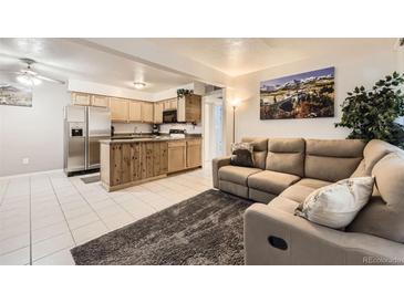 Inviting living room featuring an open floor plan, natural wood kitchen, and a comfortable reclining sofa at 3663 S Sheridan Blvd # 14, Denver, CO 80235
