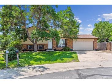Charming two-story home with a brick facade, attached garage, and mature trees in a sunny, landscaped front yard at 5372 E 108Th Pl, Thornton, CO 80233