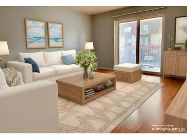 Bright living room featuring a white sofa, wood coffee table, area rug, and access to a balcony at 7755 E Quincy Ave # 203A6, Denver, CO 80237