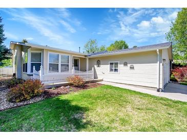 Charming single-story home showcasing a manicured lawn and a classic white picket fence at 7870 Sunflower Green # 151, Frederick, CO 80530