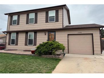 Charming two-story home with a tan exterior, brown trim, and a well-manicured front yard at 17882 E Wyoming Pl, Aurora, CO 80017
