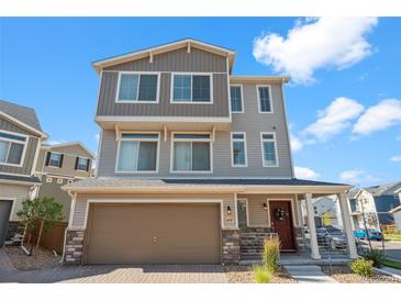 Attractive three-story home with a two-car garage, covered porch, and neutral-toned siding and brick accents at 10152 Xanadu St, Commerce City, CO 80022