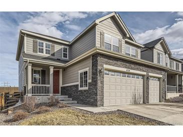 Two story home with grey siding and stone accents, a two car garage, and covered porch at 4724 S Wenatchee Cir, Aurora, CO 80015