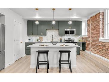 Modern kitchen boasts an island with seating, gray cabinets, updated appliances, and stylish pendant lighting at 1210 E Colfax Ave # 104, Denver, CO 80218