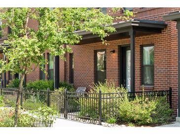 Charming brick townhouse with lush landscaping and a cozy front patio and black metal fence at 771 24Th St, Denver, CO 80205