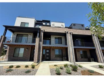 Modern townhomes with brick facade, private balconies, and manicured landscaping under a clear blue sky at 8321 Mount Kataka St, Littleton, CO 80125