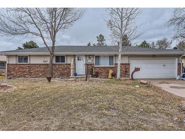 Charming single-story home with brick accents, a well-maintained lawn, and attached two-car garage at 5738 W Canyon Ave, Littleton, CO 80128