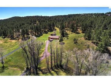 Stunning aerial view of a home with a long driveway surrounded by lush greenery and mountain views at 1971 Kerr Gulch Rd, Evergreen, CO 80439