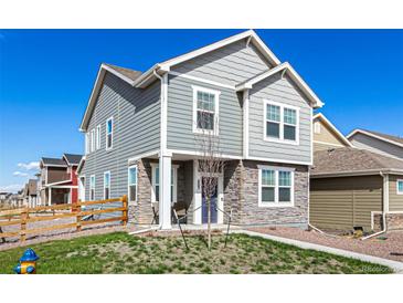 Charming two-story home features stone accents, light gray siding and a well-manicured lawn at 803 N Bently St, Watkins, CO 80137