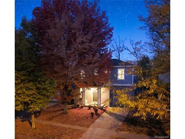 Charming two-story home with a well-maintained front yard and colorful trees at dusk at 3674 Dexter St, Denver, CO 80207