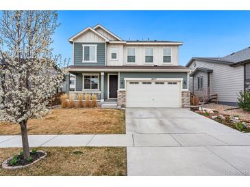 Charming two-story home featuring a manicured lawn, a two-car garage, and a welcoming front porch at 18077 E 99Th Ave, Commerce City, CO 80022