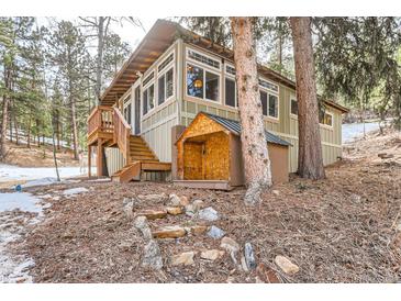 Charming home featuring a wooden porch, large windows, and lush surroundings at 30690 Highway 72, Golden, CO 80403