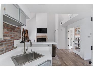 Well-lit kitchen with stainless steel sink, brick wall accent, and white countertops at 4824 E Kentucky Ave # F, Denver, CO 80246