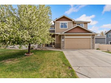 Inviting two-story home with a well-manicured lawn and a blossoming tree at 5452 Rustic Ave, Firestone, CO 80504