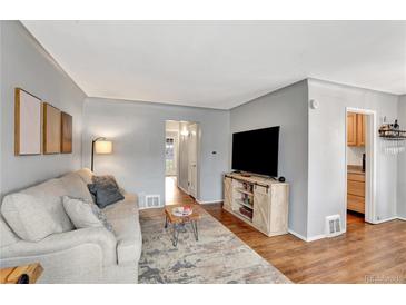 Relaxing living room with stylish decor, wood floors, and bright natural light streaming through open doorway at 1269 Krameria St, Denver, CO 80220