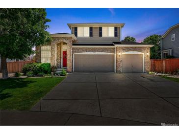 Charming two-story home with a brick facade, manicured lawn, and a two-car garage, perfect for a growing Gathering at 16863 Trail View Cir, Parker, CO 80134