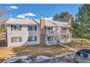 Charming condo with stone chimney, second-story balconies, manicured lawn, and car in the parking lot at 14473 E Jewell Ave # 202, Aurora, CO 80012