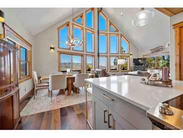 Bright dining area featuring hardwood floors, large windows with views, and a modern chandelier at 538 Sawmill Creek Rd, Evergreen, CO 80439
