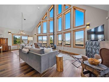 Spacious living room featuring floor-to-ceiling windows with stunning views and hardwood floors at 538 Sawmill Creek Rd, Evergreen, CO 80439
