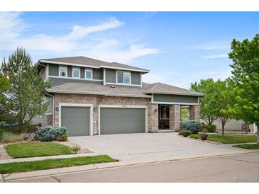 Beautiful two-story home featuring stone accents, gray siding, three-car garage, and professionally landscaped front yard at 4421 Tanager Trl, Broomfield, CO 80023