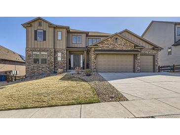 Beautiful two-story home with a stone and siding exterior, three-car garage, and landscaped front yard at 9559 Yucca Way, Arvada, CO 80007