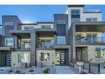 Modern three-story townhome with gray and white exterior, balconies, and a blue front door at 1756 Peak Loop, Broomfield, CO 80023