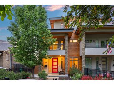 Modern two-story home with stone accents, a red front door, and a small balcony overlooking the landscaped front yard at 3845 N Raleigh St, Denver, CO 80212