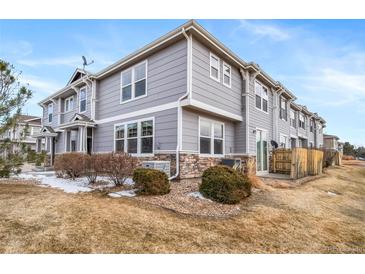 Beautiful townhome exterior with gray siding, stone accents, manicured landscaping, and a private patio at 17127 Lark Water Ln # D, Parker, CO 80134