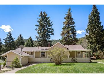 Charming single-story home with a covered front porch, mature trees, and well-maintained landscaping at 10049 S Turkey Creek Rd, Morrison, CO 80465