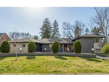 Charming single-story home featuring a lush lawn, garden beds, and a neatly paved driveway leading to an attached garage at 55 Dexter St, Denver, CO 80220