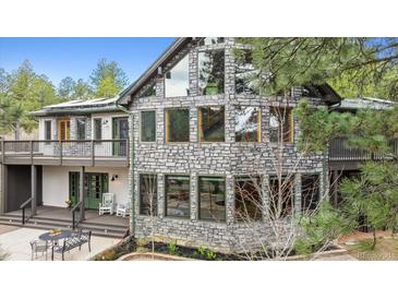 Striking stone house featuring many windows, a deck, and a covered porch with outdoor seating at 7317 Fremont Pl, Larkspur, CO 80118