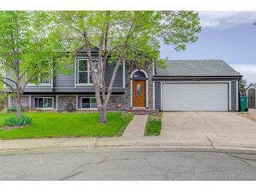 Charming gray home featuring stone accents, manicured lawn, and an attached two-car garage at 5861 S Orleans Way, Centennial, CO 80015