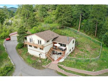 An exterior view of a two-story home featuring a deck, patio, fencing, and a detached garage at 9648 Yegge Rd, Morrison, CO 80465