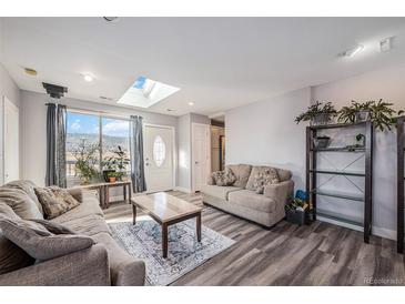 Inviting living room with two sofas, wood-look floors, skylight, and view of the mountains at 208 Wark Ave, Berthoud, CO 80513