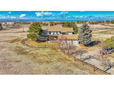 Sprawling two-story home with a stone facade, attached garage, mature trees, and ranch-style fencing around the property at 12925 Sierra Cir, Parker, CO 80138