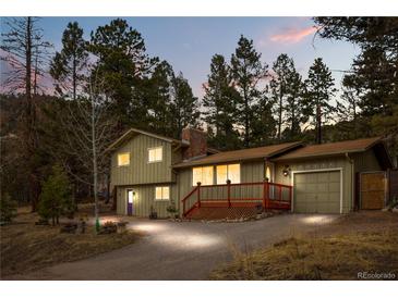 Inviting two-story home featuring a charming front porch and attached garage nestled among tall pine trees at 31219 Florence Rd, Conifer, CO 80433
