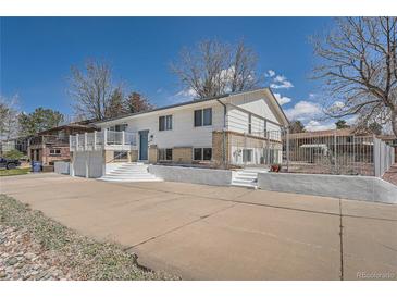 Charming raised ranch-style home featuring white exterior, brick accents, and well-maintained landscaping at 4090 S Tamarac Dr, Denver, CO 80237