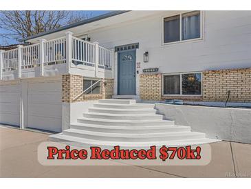 Inviting home featuring a blue front door, brick accents, and a welcoming white staircase at 4090 S Tamarac Dr, Denver, CO 80237