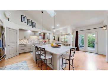 Bright kitchen with a skylight, marble island, stainless steel appliances, and bar stool seating at 6503 Big Horn Trl, Littleton, CO 80125
