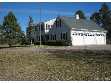Classic home exterior featuring a three car garage, mature trees and well-maintained landscaping at 2879 Gold Creek Dr, Elizabeth, CO 80107