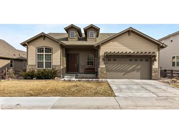 Tan two-story house with a brown door and attached garage at 14240 Ivanhoe St, Thornton, CO 80602