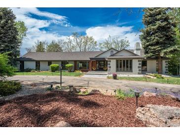 Stunning home with mature trees, circular driveway, and beautifully landscaped front yard, all under a bright blue sky at 4285 S Hudson Pkwy, Englewood, CO 80113