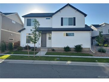 Charming two-story home featuring a white exterior, a dark roof, and a well-manicured lawn at 10136 Worchester St, Commerce City, CO 80022