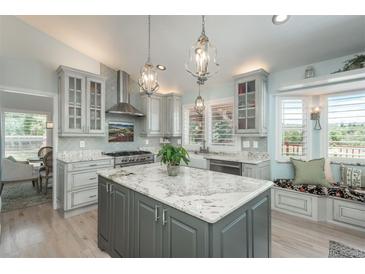 A spacious kitchen features a center island, pendant lighting, stainless steel appliances, and light colored cabinets at 3488 Dawson Rd, Sedalia, CO 80135