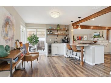 Modern kitchen features wood floors, a bar area, an island, and updated appliances at 5149 E Links Cir, Centennial, CO 80122