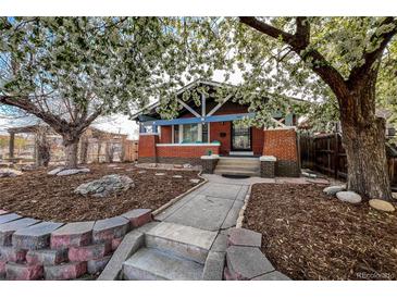 Charming brick home featuring a landscaped front yard, stone walkway, and flowering trees at 241 N Grant St, Denver, CO 80203