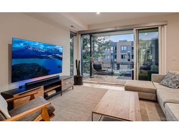 Bright living room with large TV and sliding glass doors to balcony overlooking city views at 3232 W 16 Ave, Denver, CO 80204