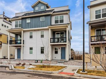 Charming three-story townhome featuring a blue door, small patio, and well-maintained landscaping at 6162 W 28Th Ct, Wheat Ridge, CO 80214