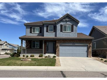 Two-story home with stone accents, gray siding, covered porch, and well-maintained landscaping at 13903 Hillsboro Dr, Parker, CO 80134